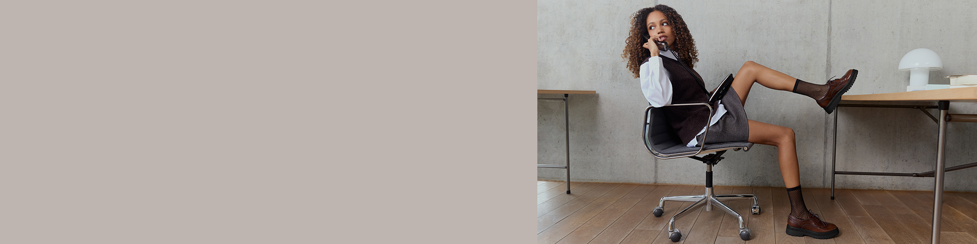 Une jeune femme d'affaires en tenue de bureau est assise de manière détendue sur une chaise pivotante et téléphone dans un bureau.