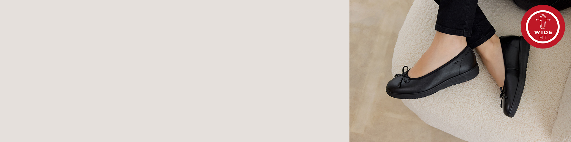 Chaussures confort noires &agrave; large chaussant et &agrave; lacets, port&eacute;es avec un pantalon noir sur une moquette claire.