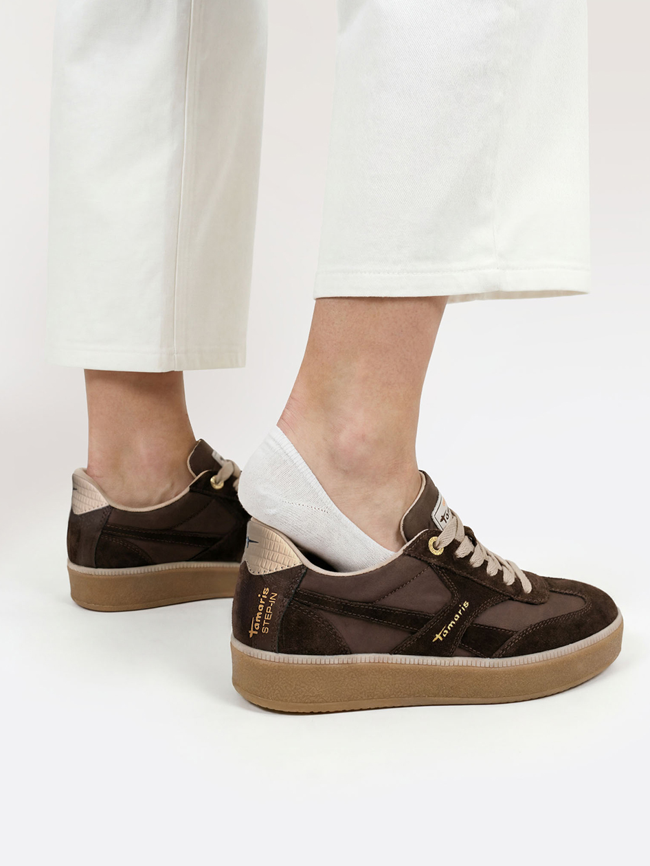 Sneakers marroni Tamaris Step-In con suola beige, abbinate a pantaloni bianchi e calzini corti.