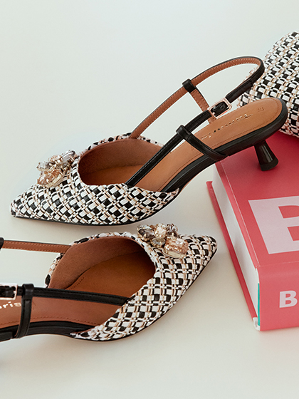 Elegante slingback‑pumps van zwart‑wit boucl&eacute; met sierstenen op de schoenneus.