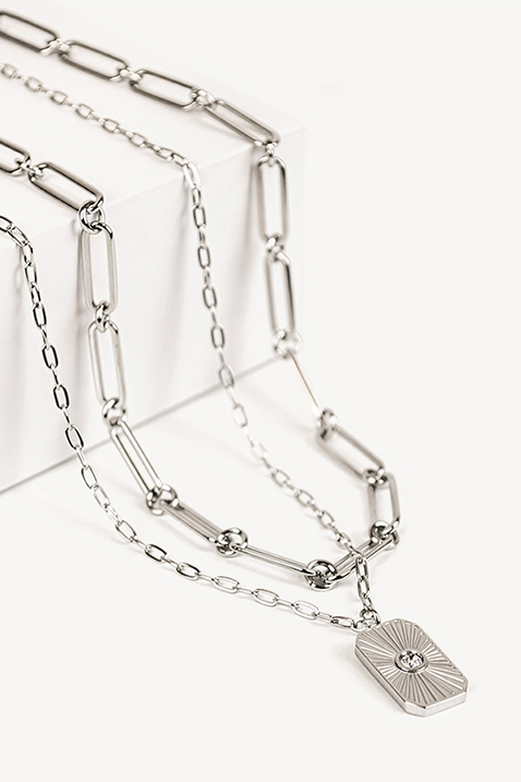 Silver link necklace with geometric pendant and crystal detailing against a white background