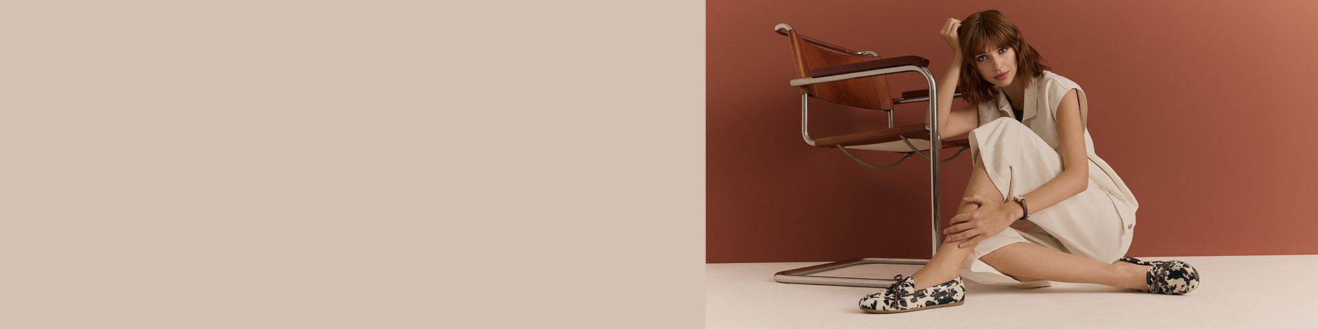 Une femme v&ecirc;tue de cr&egrave;me est assise &eacute;l&eacute;gamment au sol et porte des chaussures &agrave; motif taches de vache.