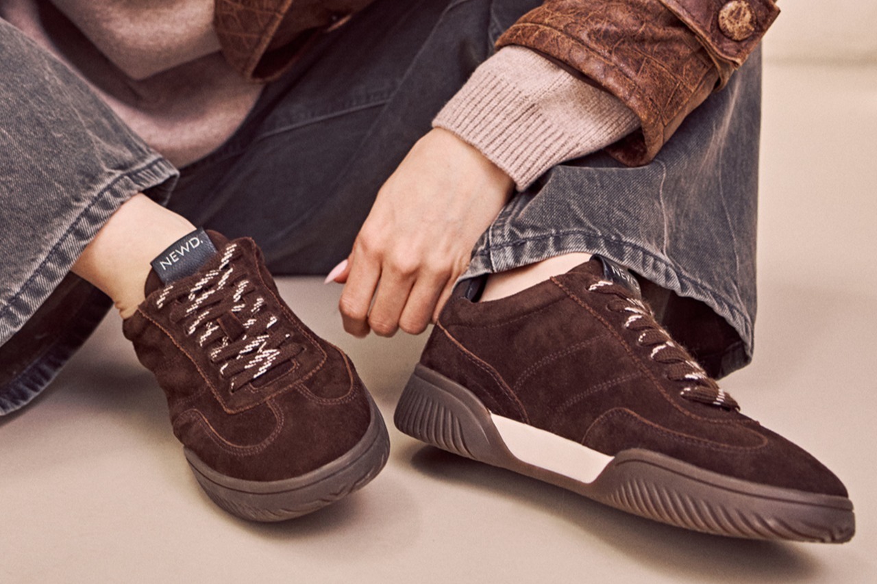 Baskets en daim marron à semelle épaisse, portées avec un jean délavé et un pull beige