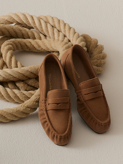 Brown Tamaris loafers on a light surface, arranged next to a thick beige rope.