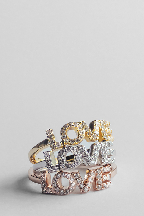 Tre glitrende ringe med ordet &ldquo;LOVE&rdquo; i forskellige metaltoner &ndash; guld, s&oslash;lv og rosaguld &ndash; med krystaludsmykning.