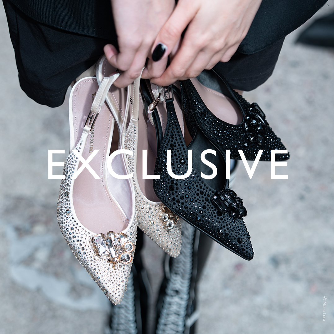 Frauenh&auml;nde halten elegante Ballerinas mit Strasssteinen in Beige und Schwarz. Schriftzug "Exclusive" im Vordergrund.