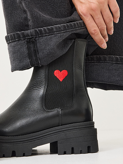 Black Chelsea boots with red heart detail on the side.