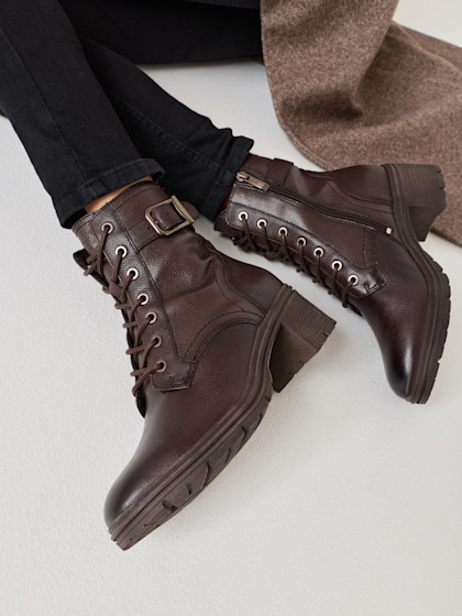 Braune Lederstiefel mit Schnürsenkeln, getragen mit schwarzen Hosen