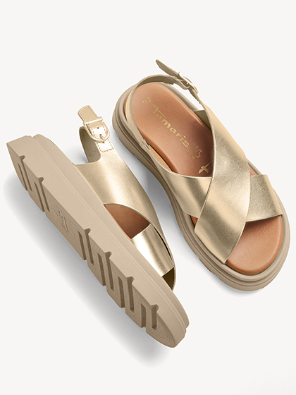 Sandali platform dorati con cinturini larghi e suola carrarmato robusta su sfondo bianco.