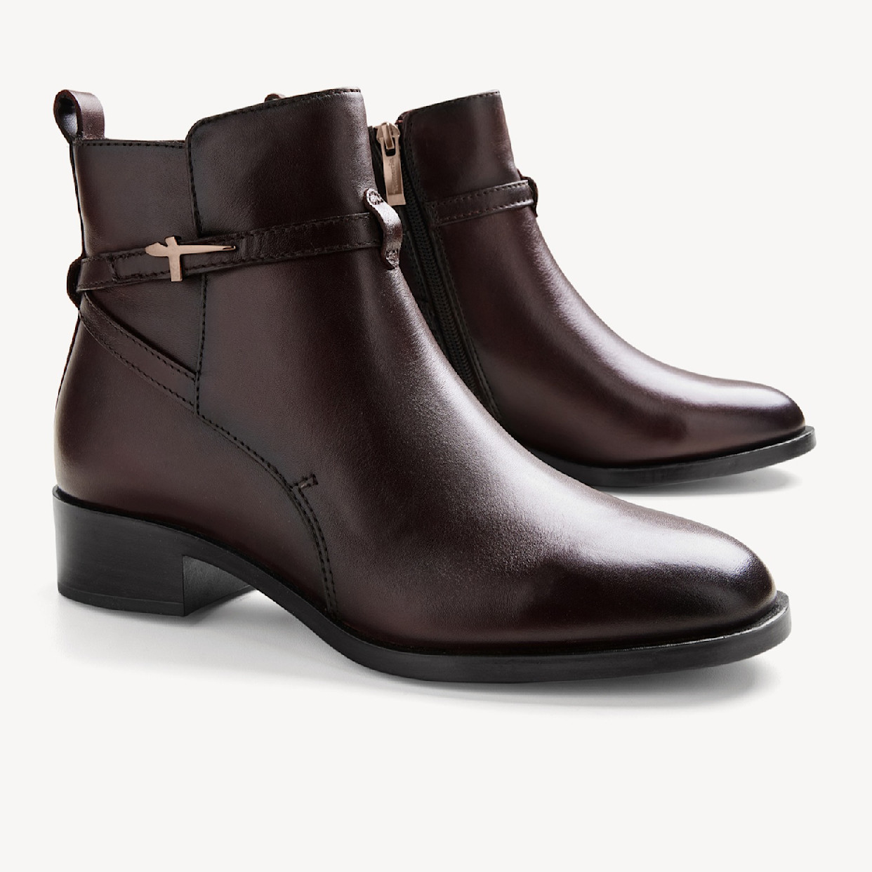 Braune Lederstiefeletten mit Absatz und goldenen Details. 