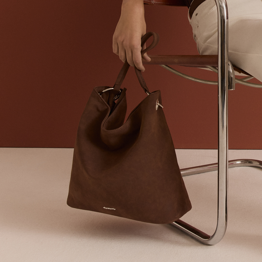 A brown handbag in front of a two-toned wall.