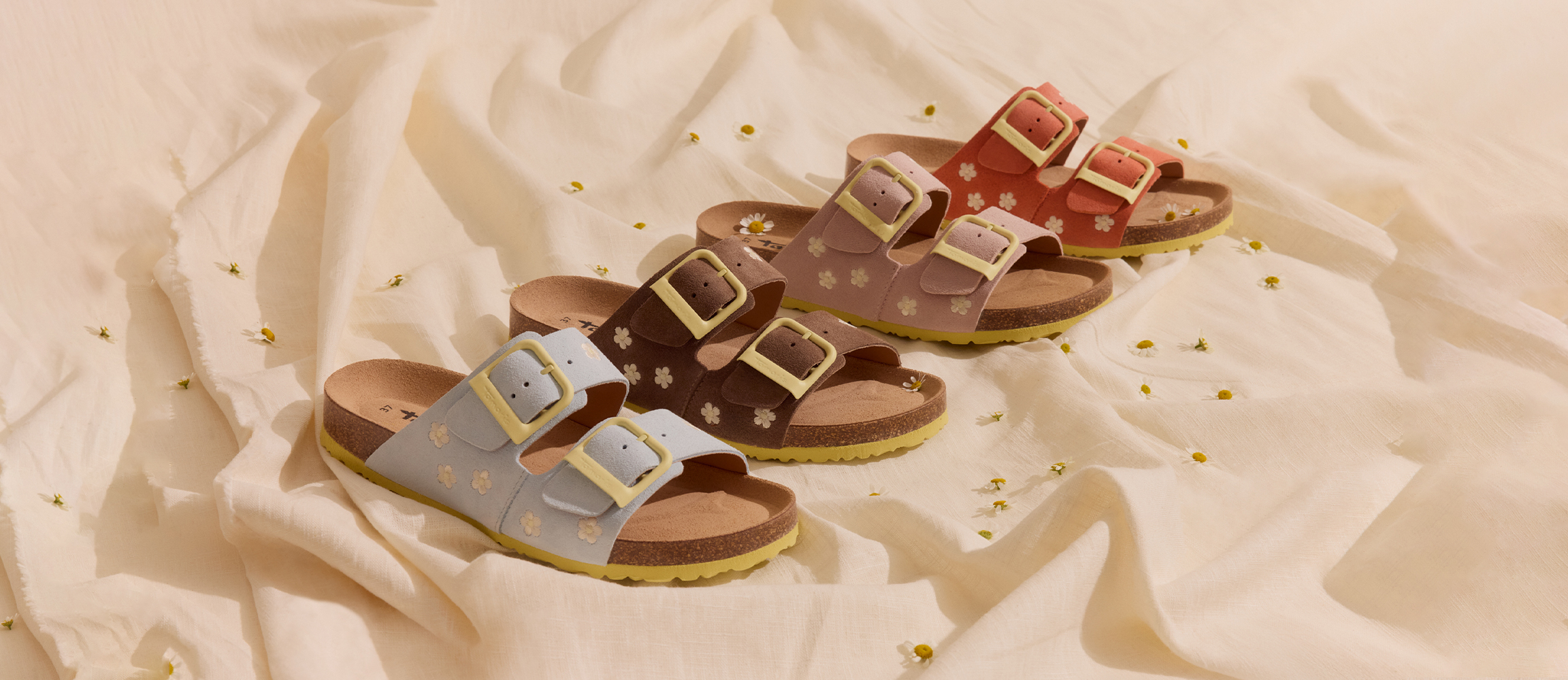 Quatre mules Tamaris &agrave; motif floral en bleu clair, marron, rose et corail avec des boucles jaunes sur un fond clair.