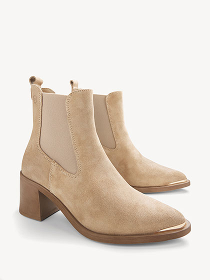 Beige suede chelsea ankle boots with gold detailing on the toe and a mid block heel.