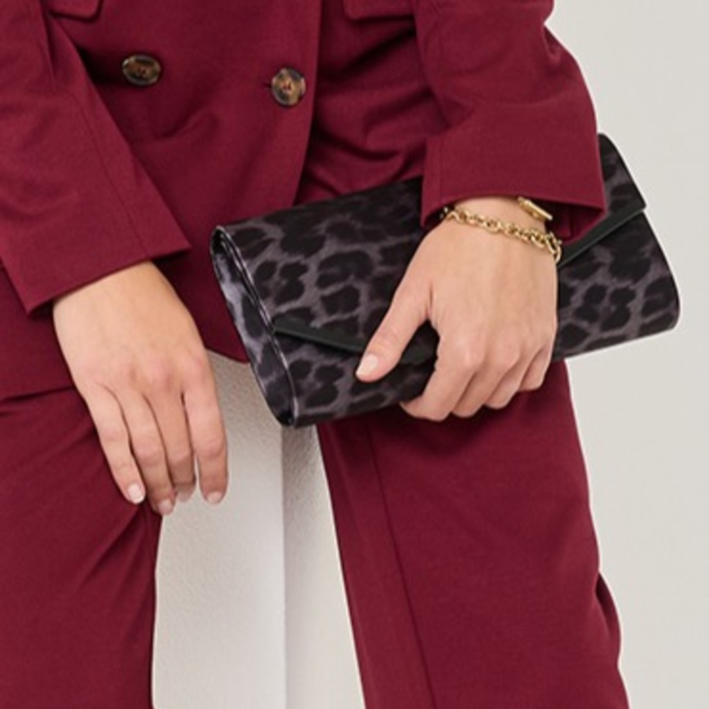 Ruce drží černou psaníčko s leopardím vzorem před vínovým sakem.