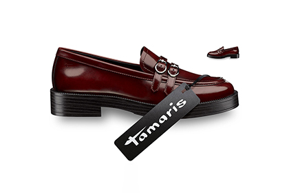 Elegant burgundy ladies loafers with black sole and Tamaris brand ribbon, photographed on a white background.