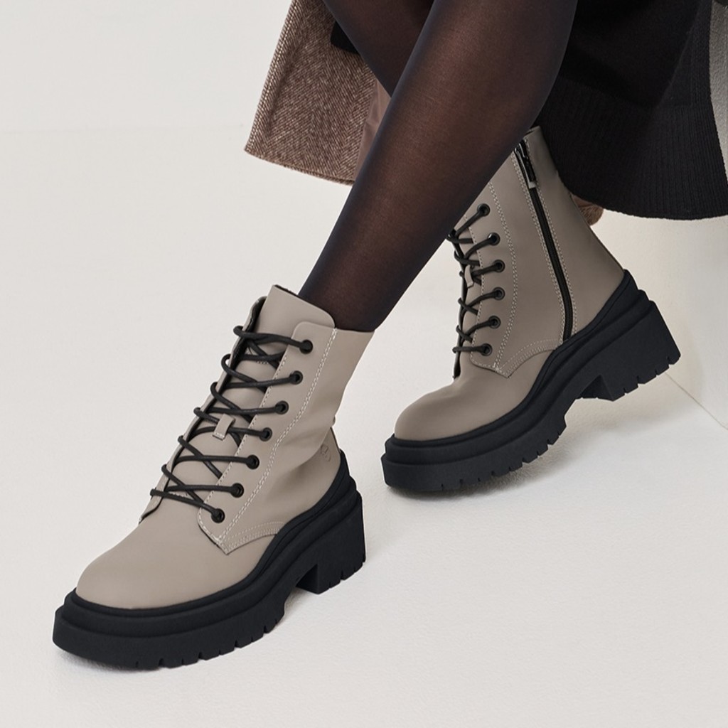 Graue Schnürstiefel mit schwarzer Plateausohle und schwarzen Schnürsenkeln, getragen mit dunklen Strumpfhosen