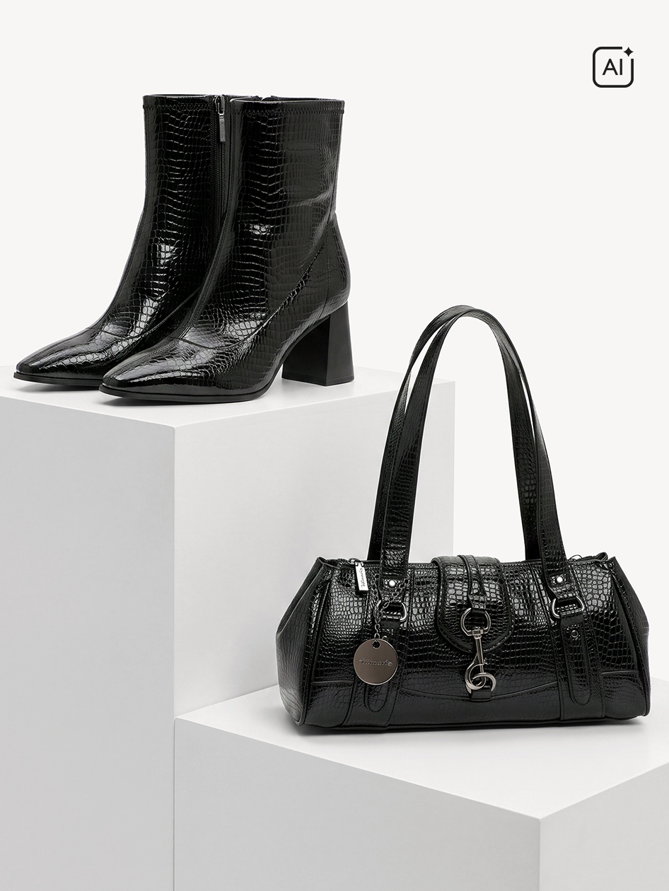 Schwarze Stiefeletten und Handtasche im Kroko-Look auf wei&szlig;en Podesten, beide mit gl&auml;nzender Oberfl&auml;che und silbernen Details.