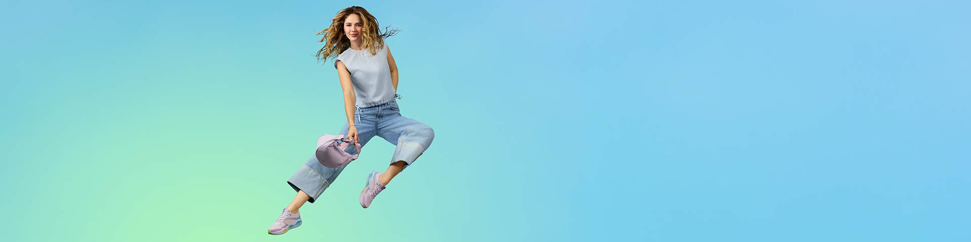Woman in casual clothing and sneakers jumps dynamically against a turquoise background.