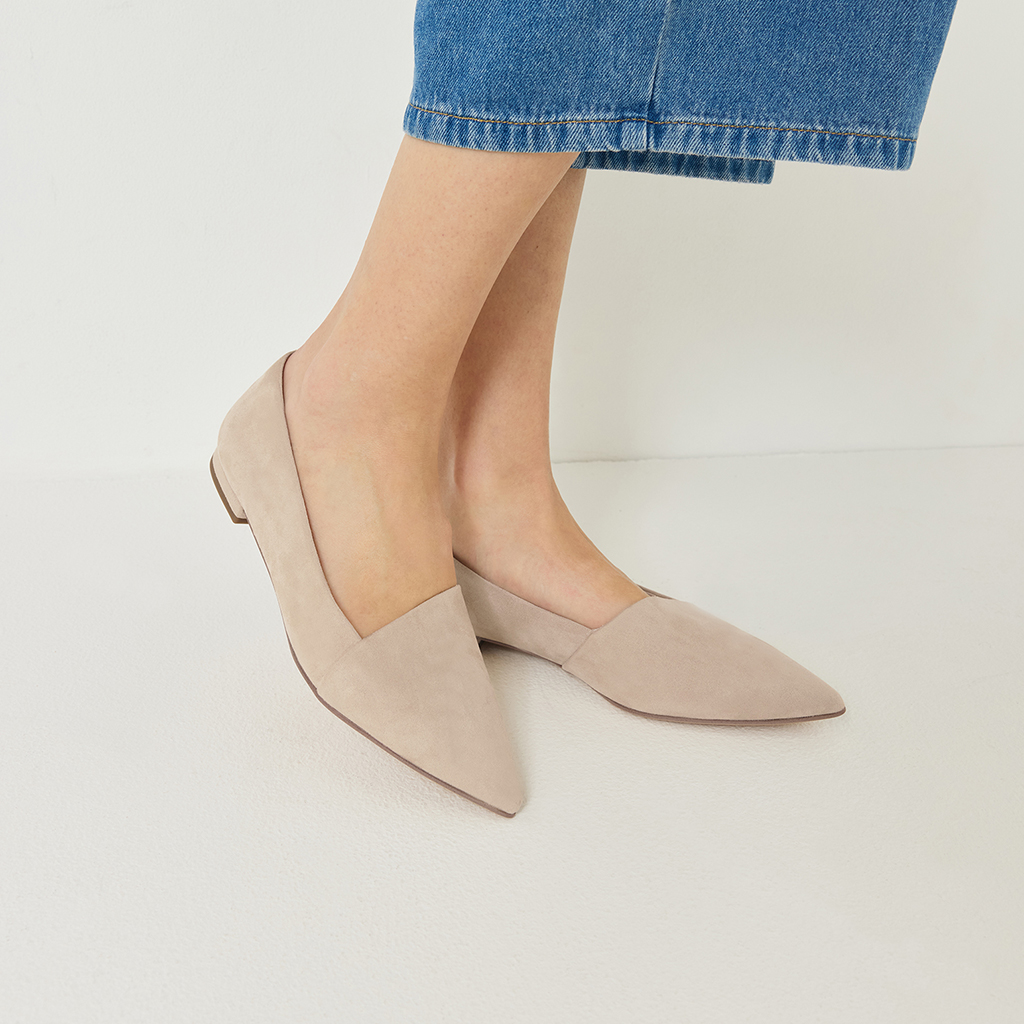 Mocassins beiges &eacute;l&eacute;gants &agrave; bout pointu, port&eacute;s avec un jean bleu sur fond blanc.