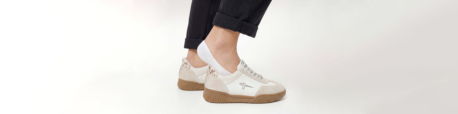 Close-up of feet slipping into beige-brown sneakers.