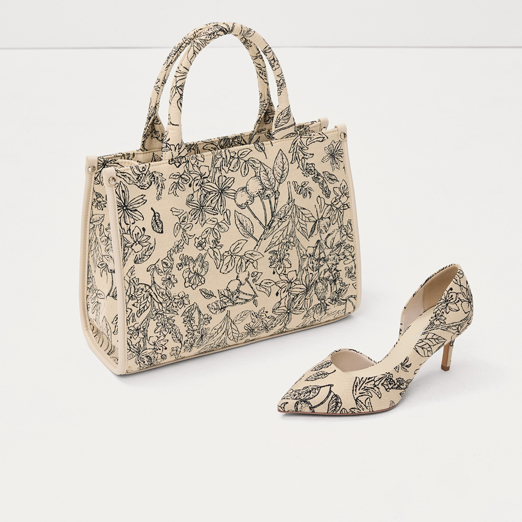 Borsa color crema e d&eacute;collet&eacute; con motivo floreale bianco e nero, elegante set di accessori su sfondo bianco.