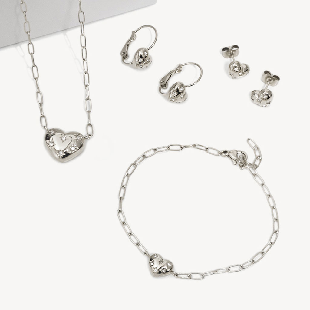 Silbernes Schmuckset mit Herzmotiv: Halskette, Armband, Creolen und Ohrstecker mit Kristallverzierungen auf wei&szlig;em Hintergrund.