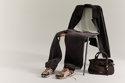 Outfit laid over a chair: dark brown jacket, white top, dark jeans, trainers and a brown handbag beside it.