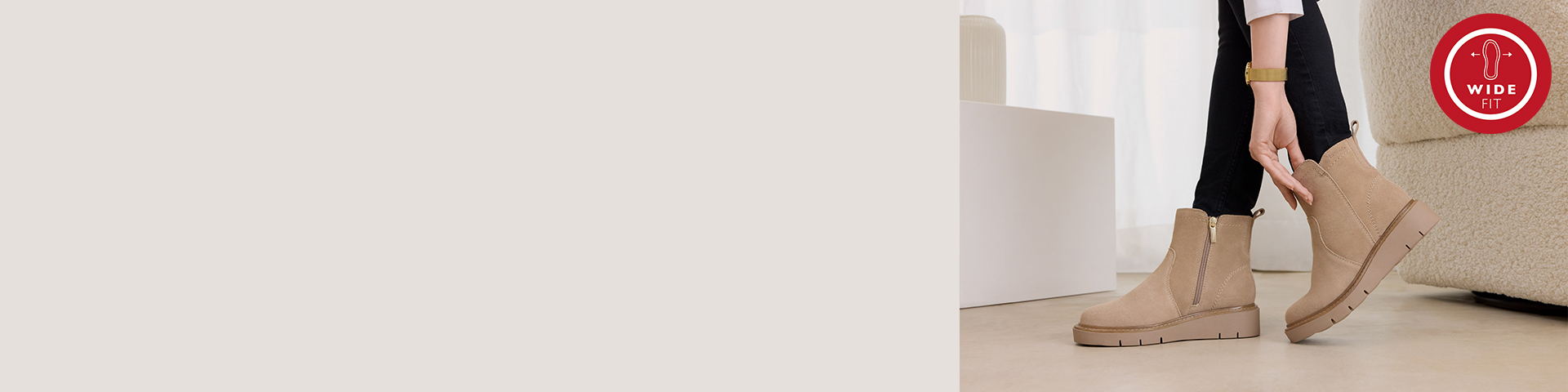 Beige Stiefel mit breiter Passform und seitlichem Rei&szlig;verschluss, getragen zu schwarzer Hose auf hellem Untergrund mit rotem Wide-Fit Logo oben rechts