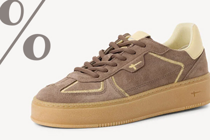 Brązowy sneaker z zamszu z kremowymi akcentami i grubą podeszwą, z znakiem procenta w tle.