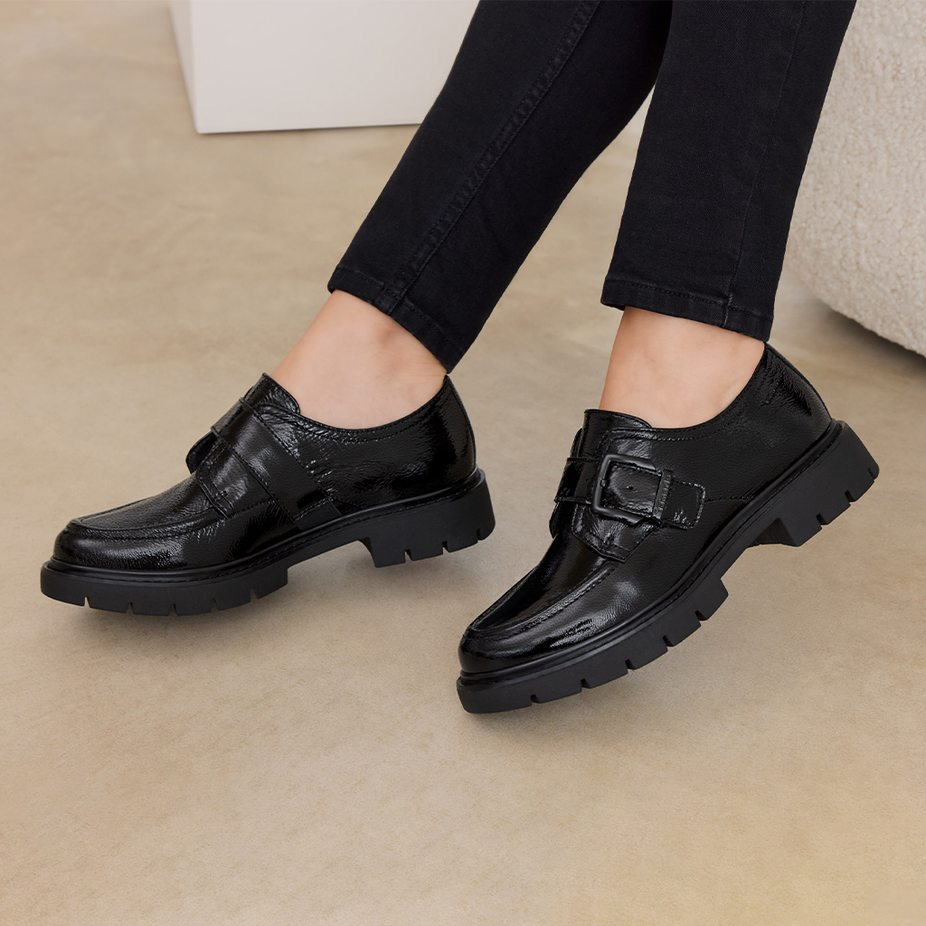 Black patent loafers with robust tread sole and buckle detail, worn with black skinny jeans