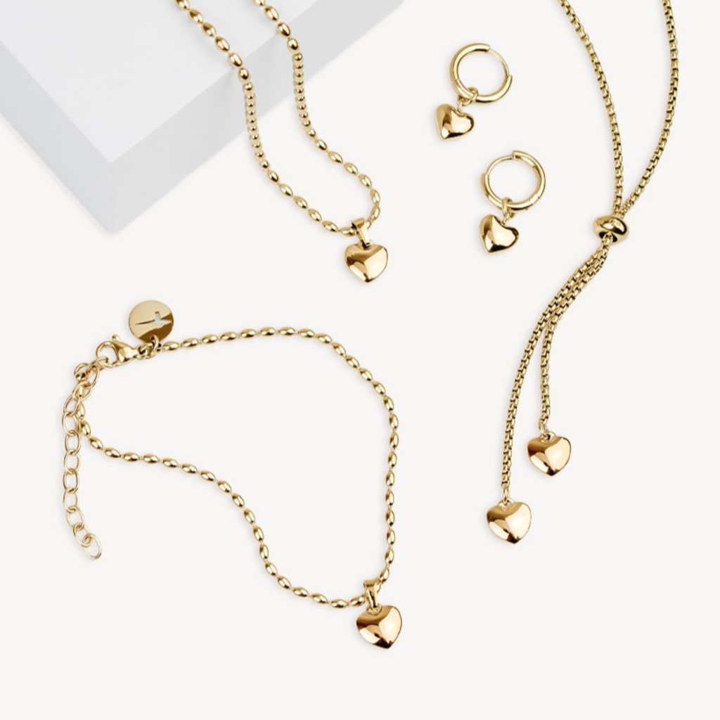 Goldenes Schmuckset mit Herz-Anh&auml;ngern auf hellem Hintergrund.