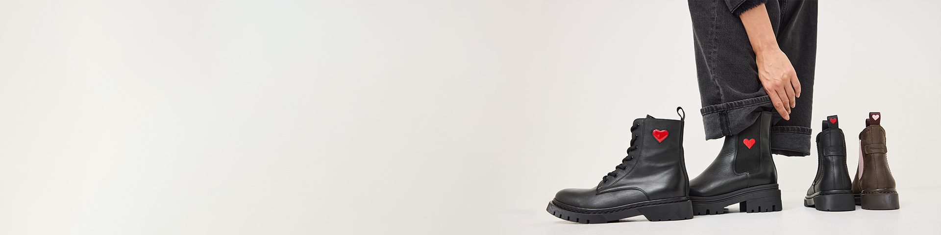 Schwarze Chelsea-Stiefel mit roten Herzen an der Seite auf weißem Hintergrund. 