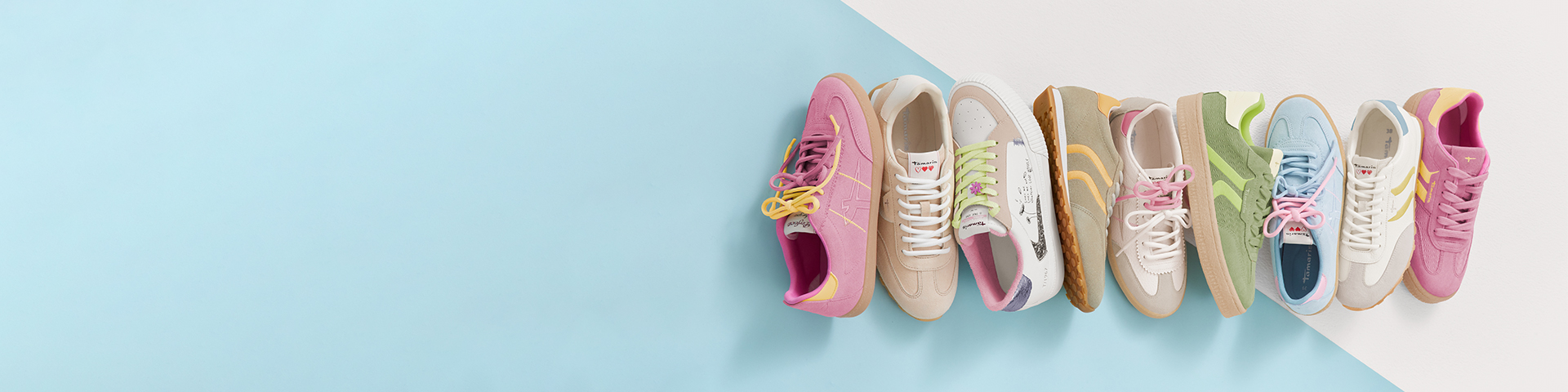 Eine Reihe bunter Sneaker in Pastellt&ouml;nen wie Rosa, Beige und Hellgr&uuml;n auf hellblauem und wei&szlig;em Hintergrund angeordnet.