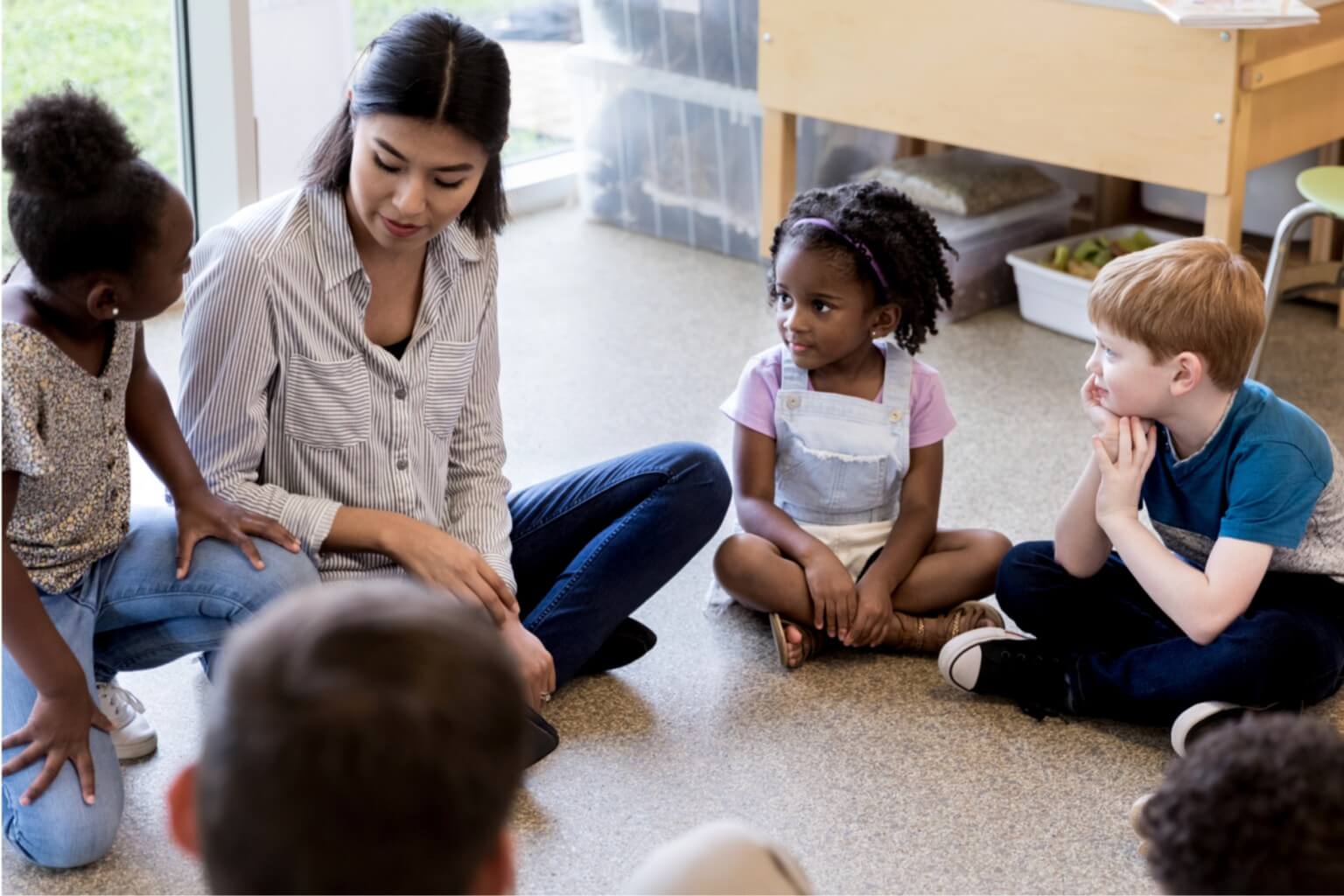 A teacher and students sitting in a circle.