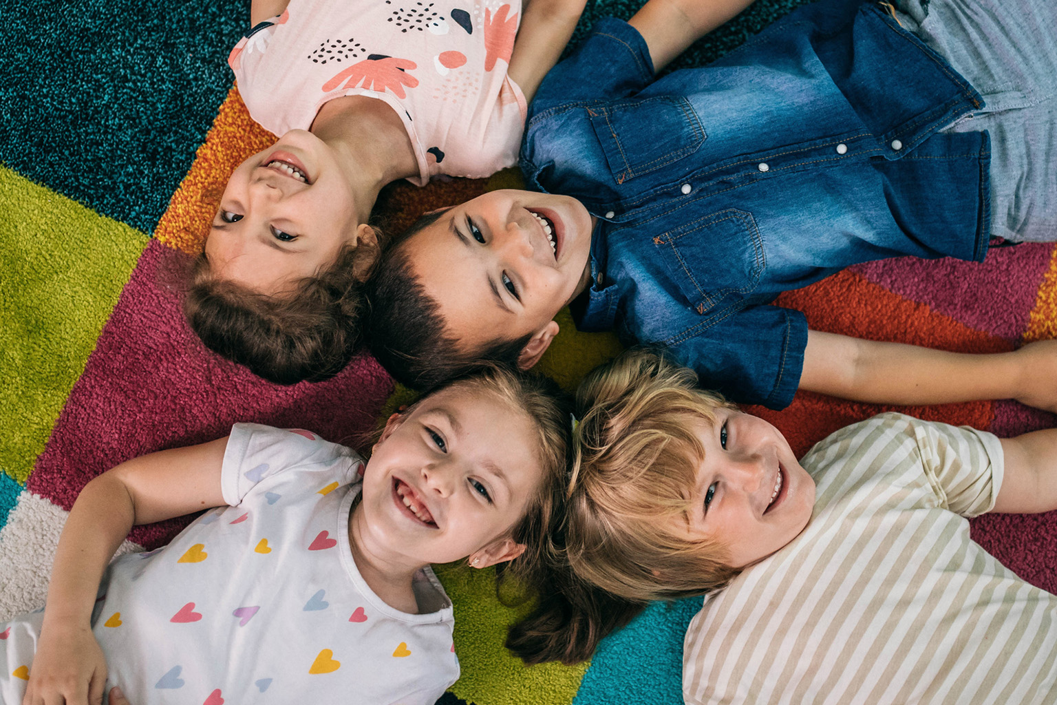 Smiling kids in a circle on the floor.