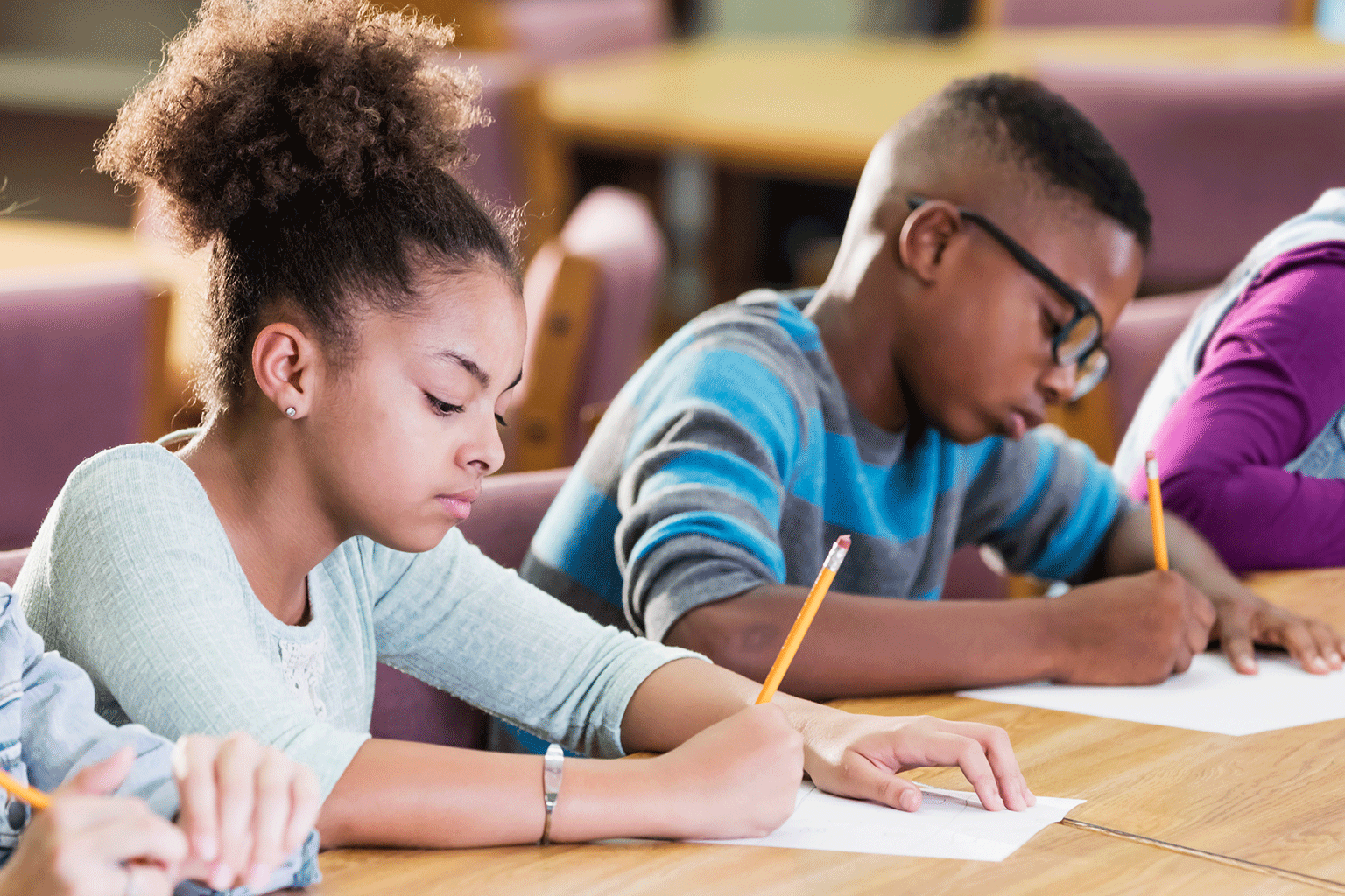 Kids writing at their desks in a classroom. 