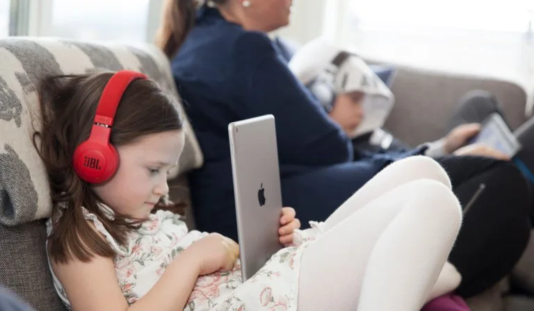 Jente med iPad Sittende jente med røde hodetelefoner og en iPad i fanget