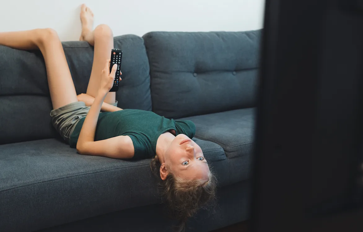 Alene etter skoletid Jente ligger oppned i sofaen og ser på tv