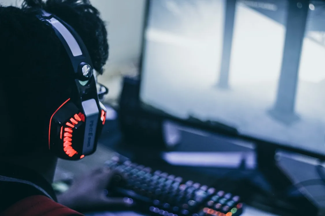 Spillservere En gutt med hodetelefoner sitter foran en PC-skjerm og spiller