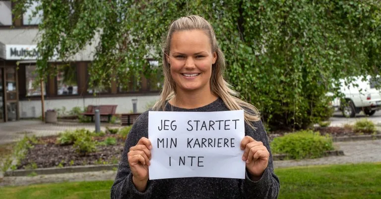 Lise Lise holder opp en plakat som sier "Jeg startet min karriere i NTE"