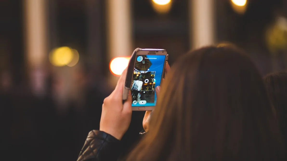 iPhone tar bilde Dame tar bilde med en iPhone med ryggen til kamera