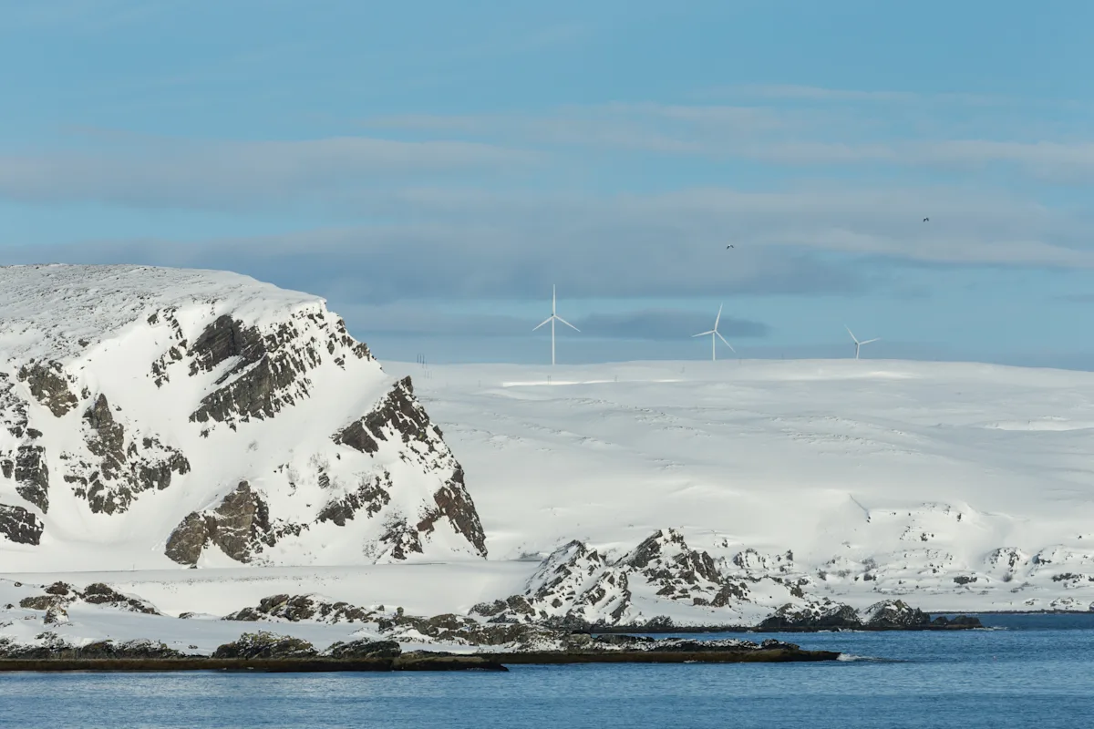 Kvitfjell Raudfjell vindkraftverk Snødekt kystlandskap med fjell og vindmøller under blå himmel