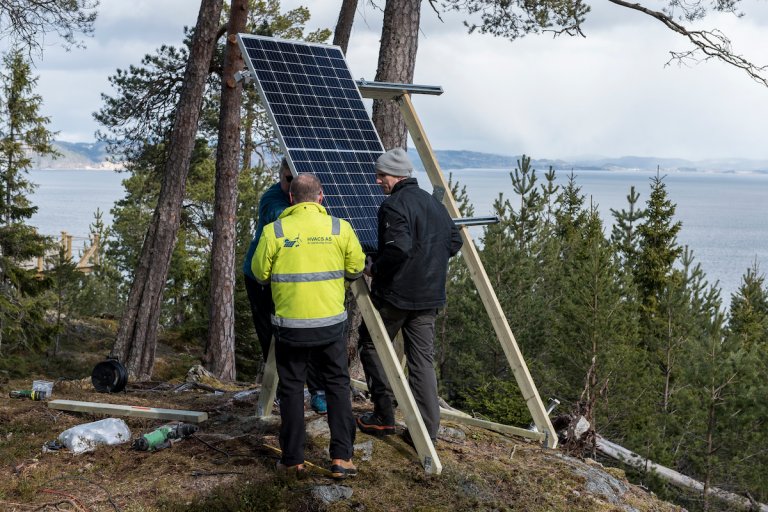Elektrikere monterer solcellepanel i skogen
