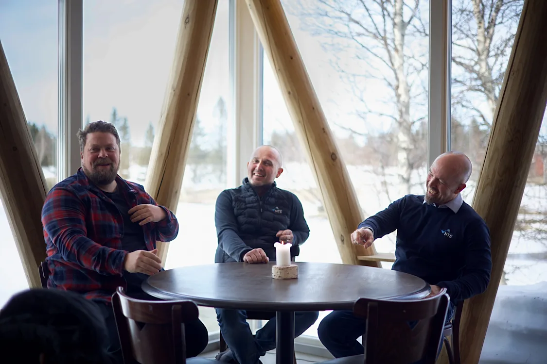 God stemning rundt bordet Tre menn sitter rundt et bord og ler