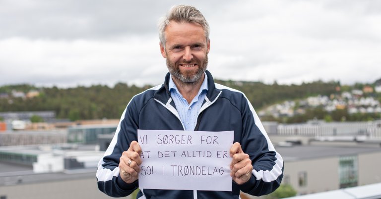 Andre Bremseth holder en plakat som sier "Vi sørger for at det alltid er sol i Trøndelag"