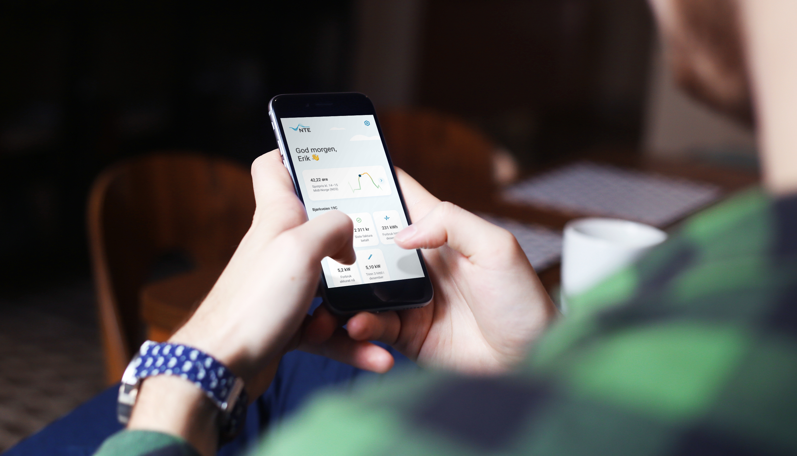 Bilde av hender som holder en mobil med forsiden på appen Mitt NTE
