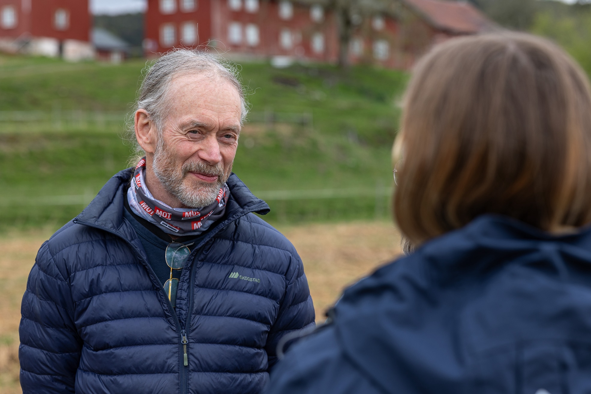 Mann med boblejakke og briller hengende rundt halsen med en buff det står MOT på