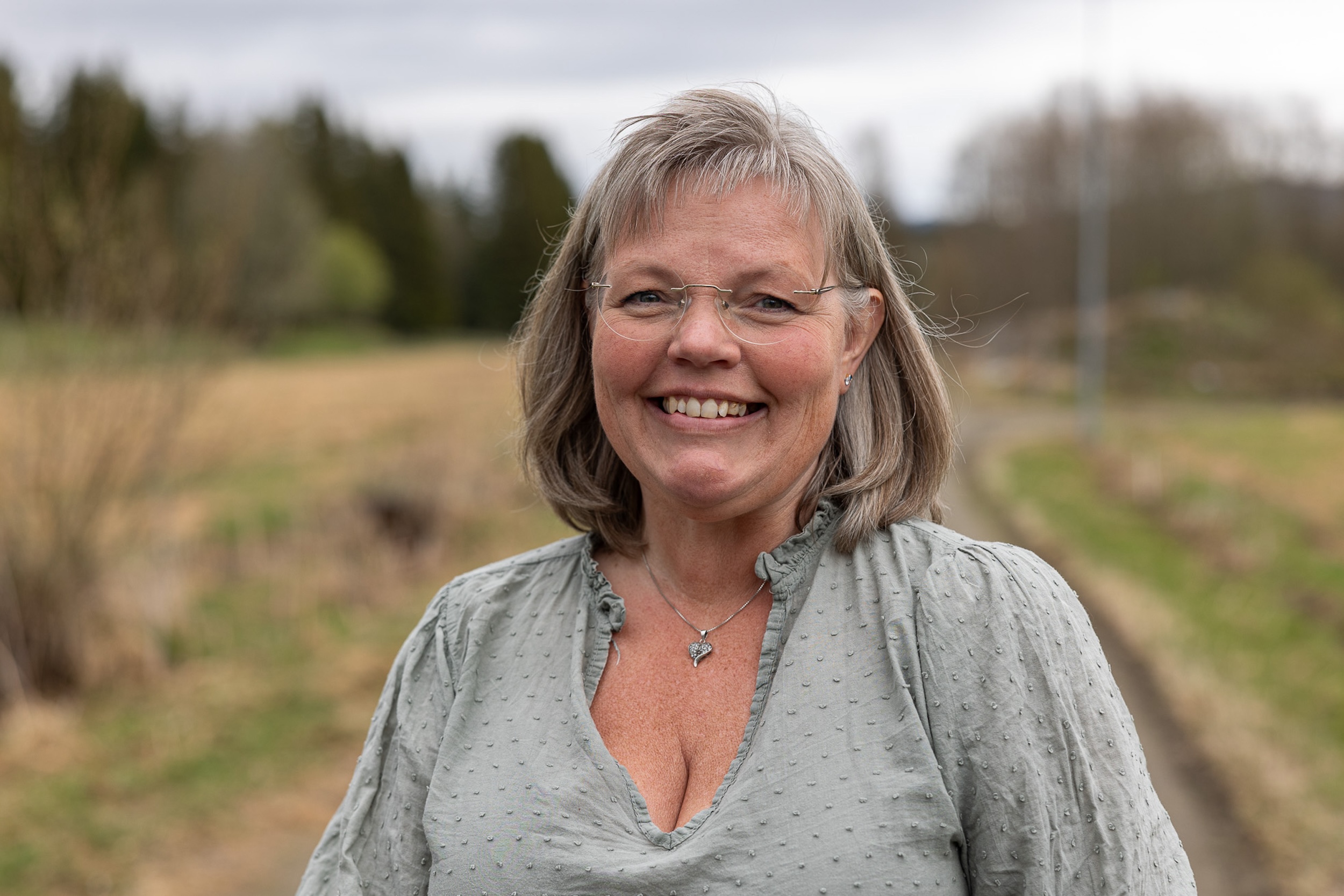 Smilende kvinne på en skogsvei