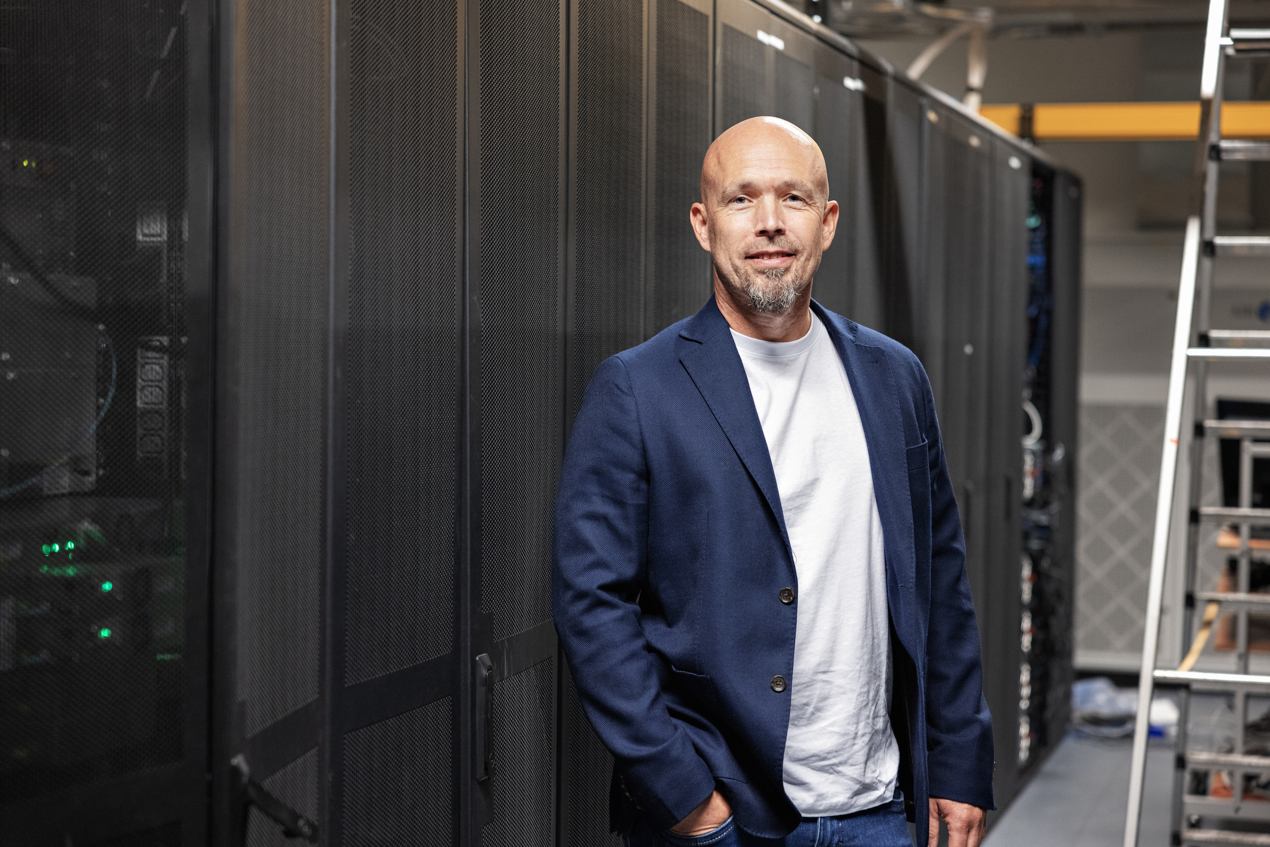 Smilende mann i dressjakke foran en lang rekke med skap