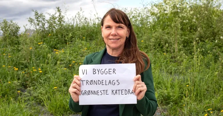 Randi Randi holder opp en plakat som sier "Vi bygger trøndelags grønneste katedral"